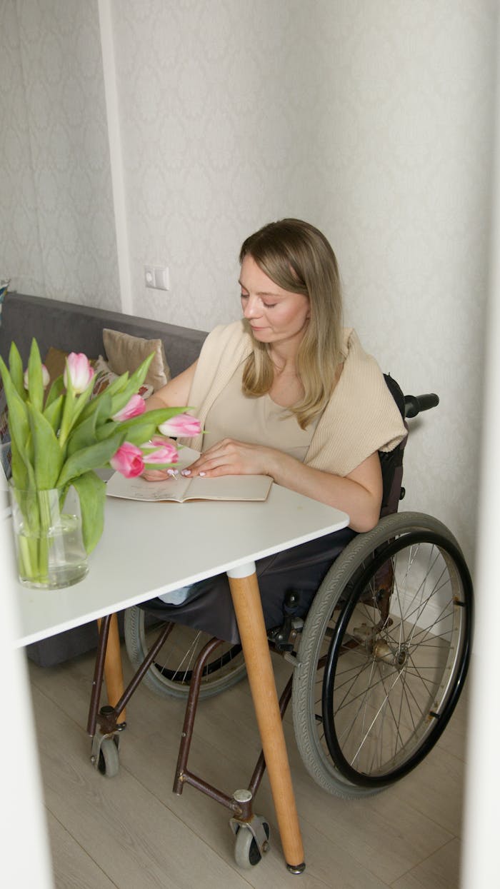 A Woman on a Wheelchair Writing on a Notebook